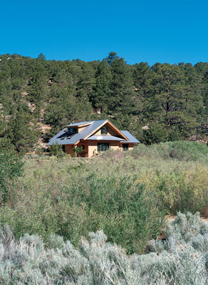 
The 1,500-square-foot econest is snuggled in a forest of ponderosa pine overlooking a field of willows. Four-foot overhangs protect the straw-clay walls, a south-facing solar room helps heat the house, and a pent roof at the gable end protects the exposed wall from driving winds and rain.
